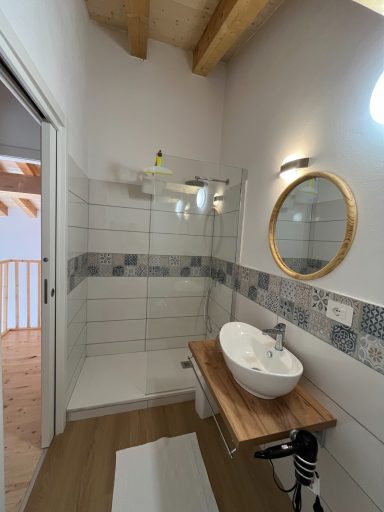 Modernes Badezimmer mit Dusche, runder Spiegelfläche und Holzwaschtisch.