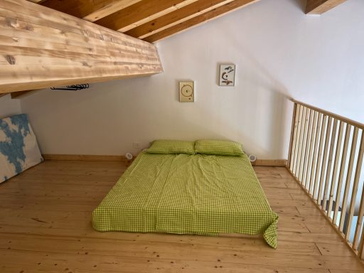 Schlafbereich mit Doppelbett und Holzdecke in einem gemütlichen Raum.