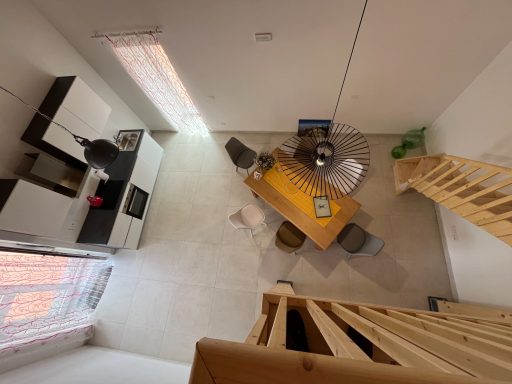 Moderne, minimalistische Wohnung mit Essbereich, Küche und Holztreppe nach oben.