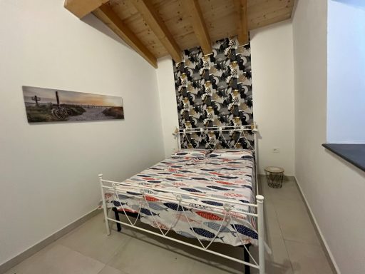 Ein einfaches Schlafzimmer mit einem Bett, buntem Bettzeug und holzbedeckter Wand.