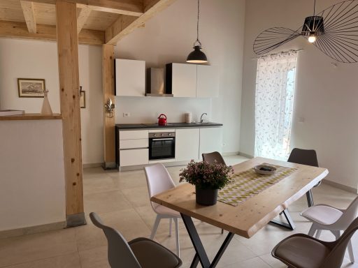Helle, moderne Küche mit Tisch, Stühlen und Fenstern für natürliche Beleuchtung.