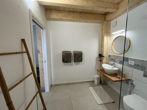 Helles Badezimmer mit Holzverkleidung, runder Spiegel und modernen sanitären Einrichtungen.