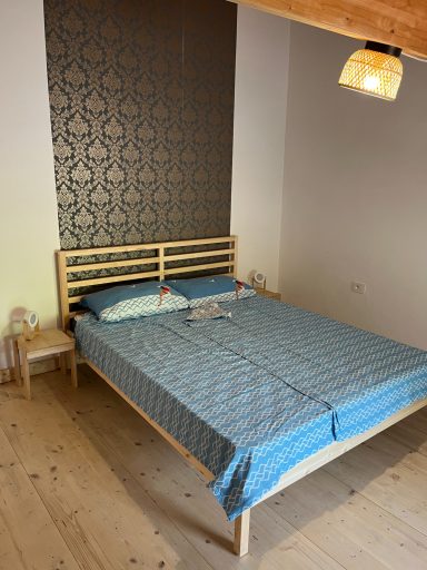 Ein Schlafzimmer mit einem Holzbett, blauer Bettwäsche und einer dekorativen Wand.