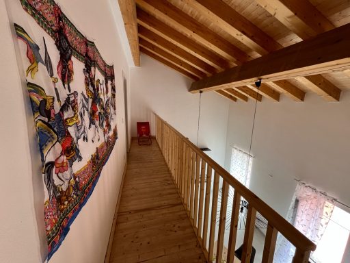 Holzdecke und Galerie mit einer farbenfrohen Wandgestaltung und einem roten Stuhl.