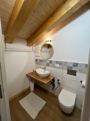 Kleines Badezimmer mit Holzregal, runder Spiegel und moderner Toilette.