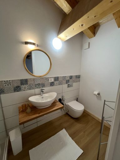 Kleines, modernes Badezimmer mit Waschbecken, Spiegel und WC, Holzdetails.