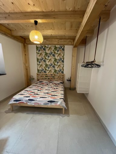 Helles Schlafzimmer mit Holzdecke, Doppelbett und einer bunten, gemusterten Wand.