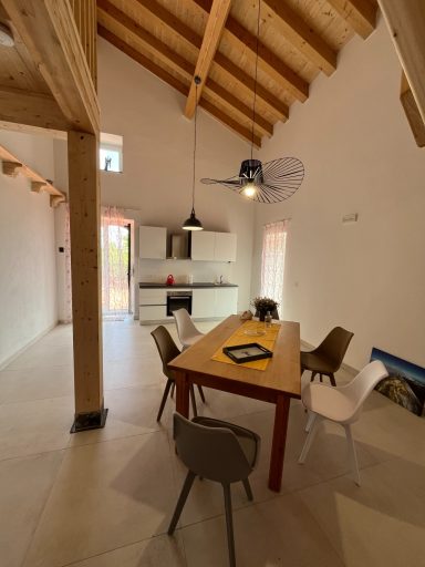 Modernes Esszimmer mit Holzdecke, Tisch und verschiedenen Stühlen in hellen Farben.