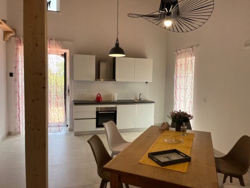 Helle, moderne Küche mit Esstisch, schwarz-weißen Möbeln und Fenstern mit Vorhängen.