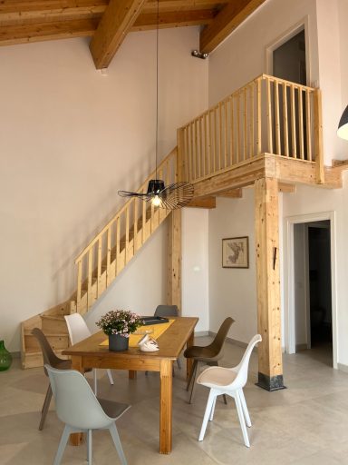 Holztreppe zu einem Balkon, Essbereich mit Tisch und Stühlen in moderner Einrichtung.